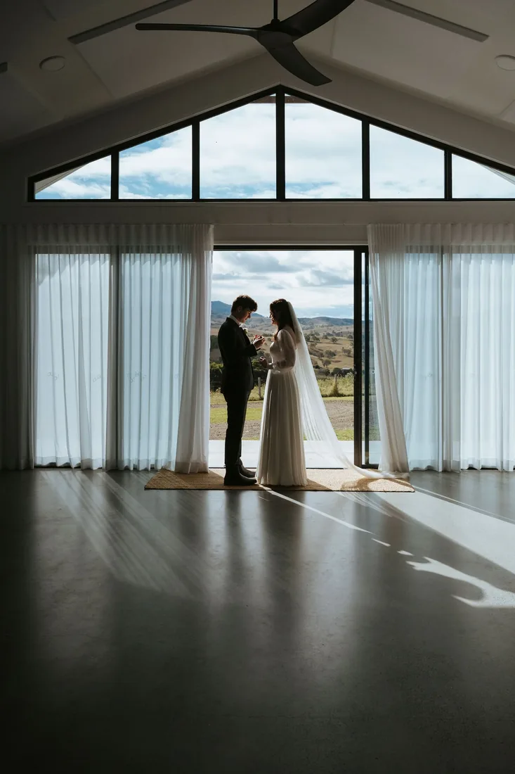 Melanie and Nathan exchanging vows in the reception doorway, mountain views behind them