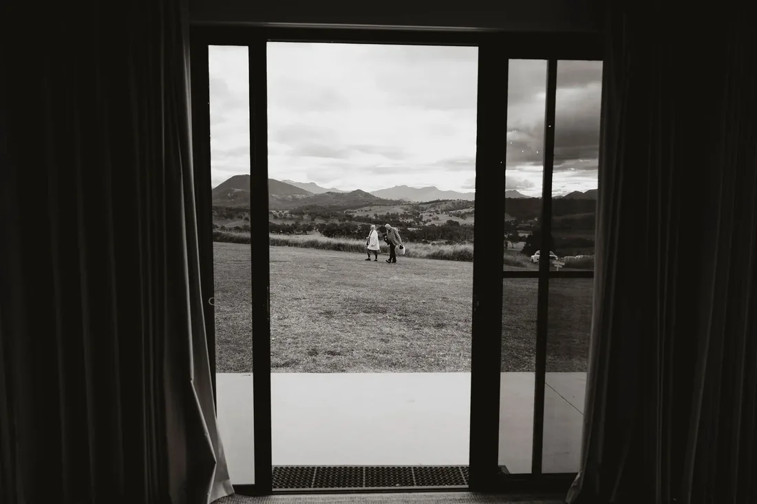 Black and white photo looking out through the reception doors to guests on the lawn