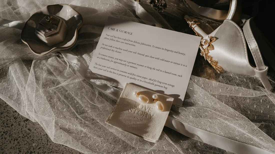 Flatlay of a wax seal favour, ring box and bridal shoe styled on a sheer veil