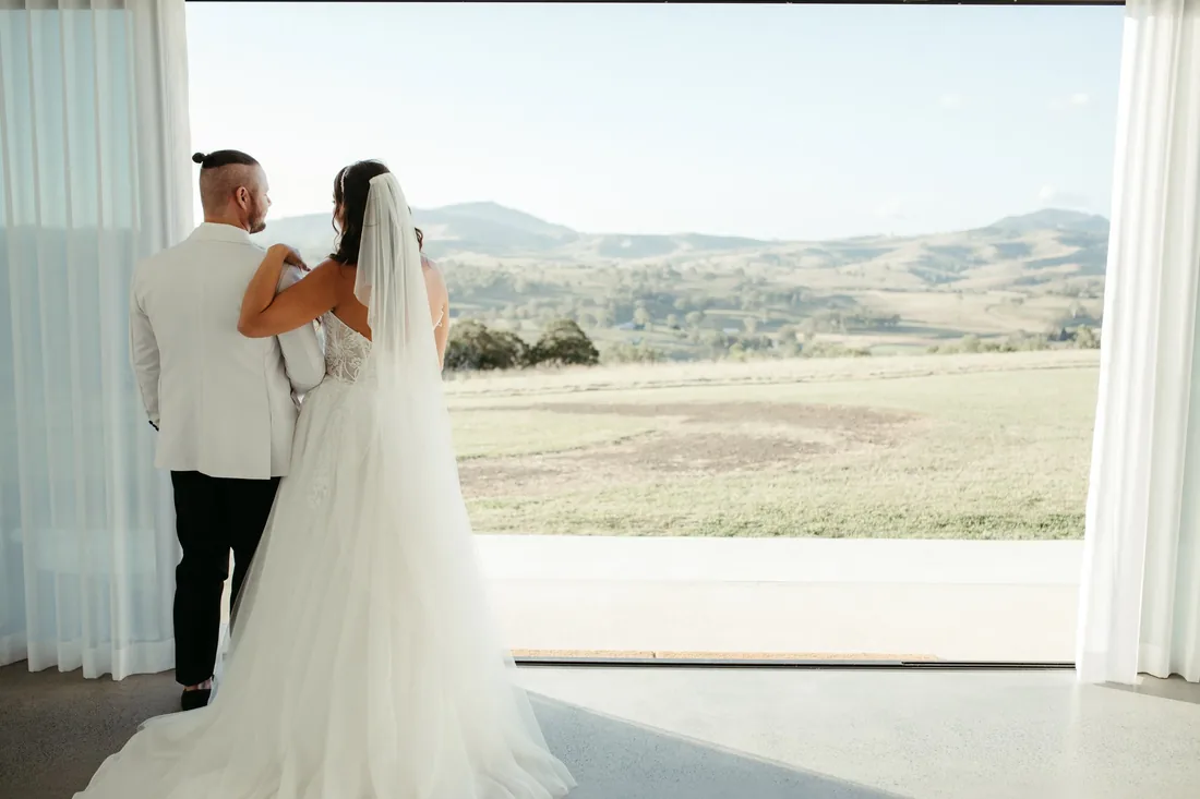 Bride and groom looking out over the Scenic Rim landscape from the reception doorway