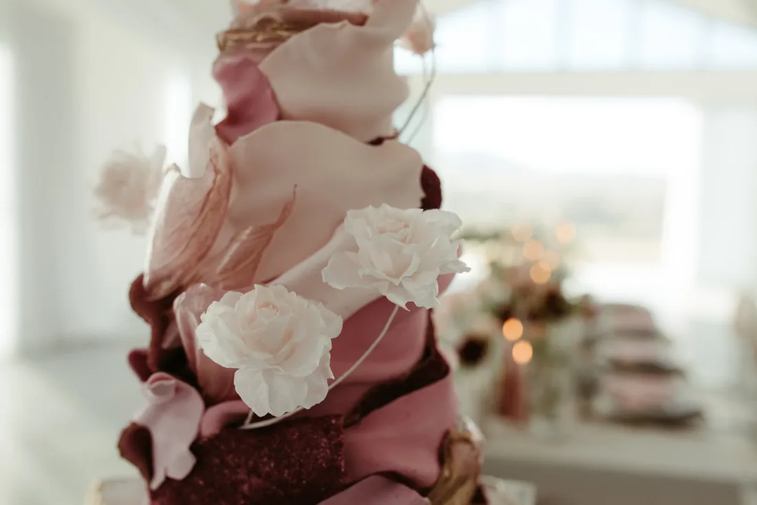 Close-up of a pink and burgundy ombre wedding cake with sugar roses