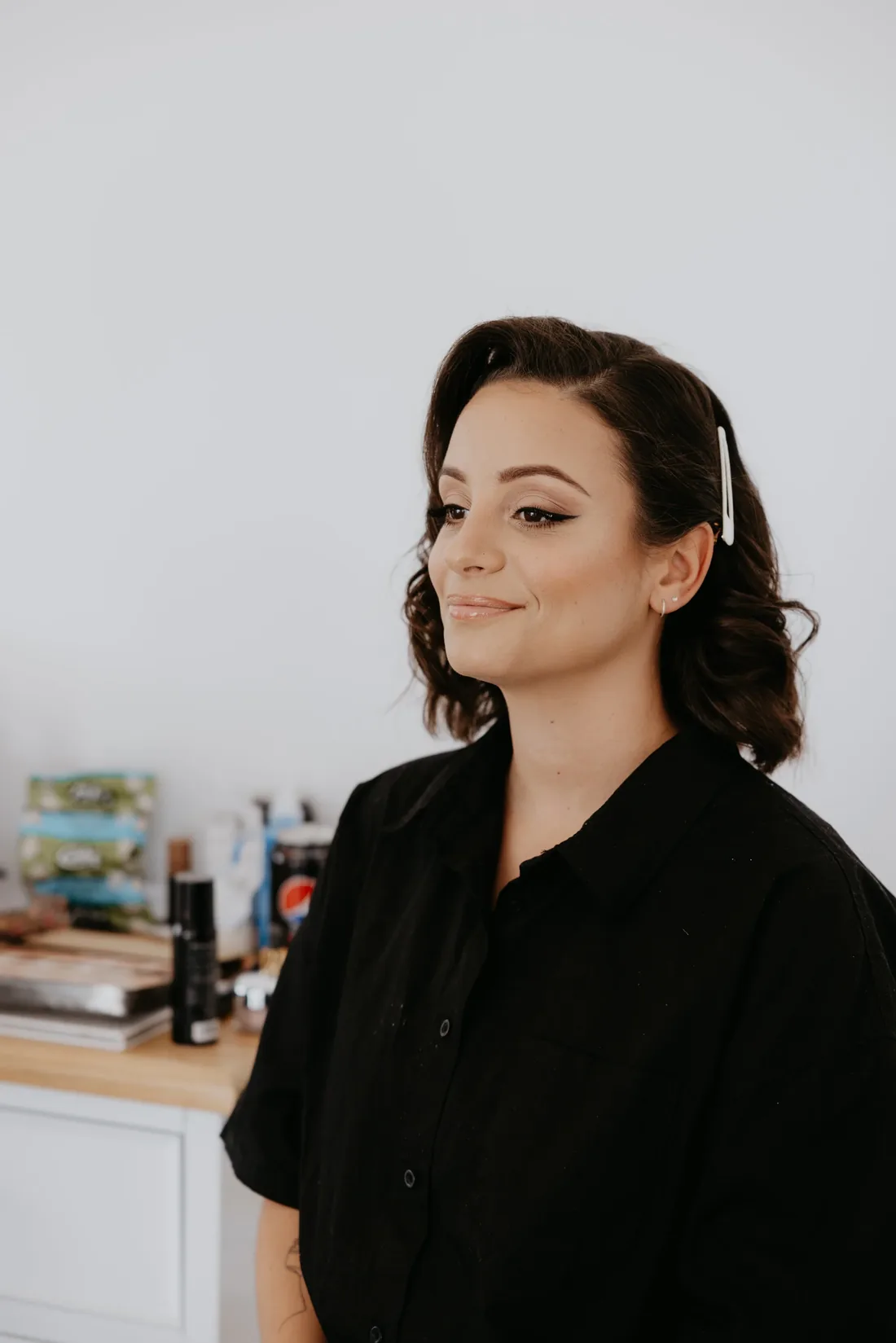 Bride getting her hair styled backstage, wearing a black robe