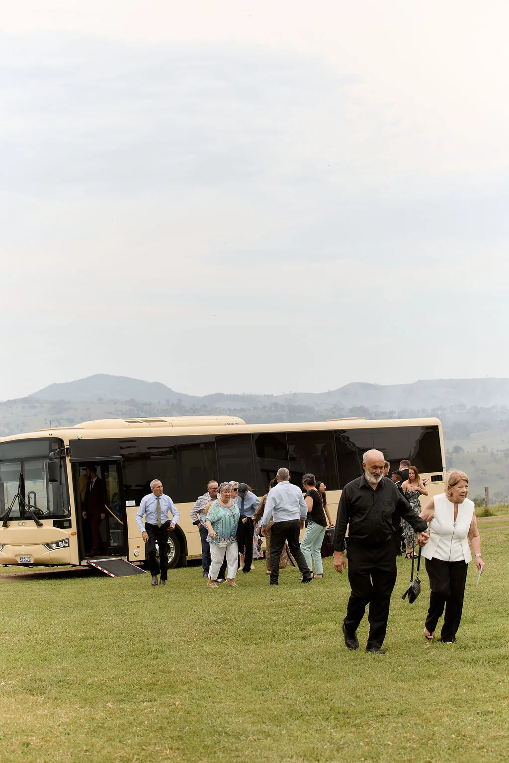 Wedding guests arriving by coach, walking across the lawn towards the ceremony