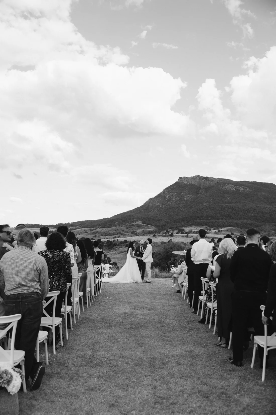 Black and white photo of the ceremony aisle, guests seated either side facing the mountains