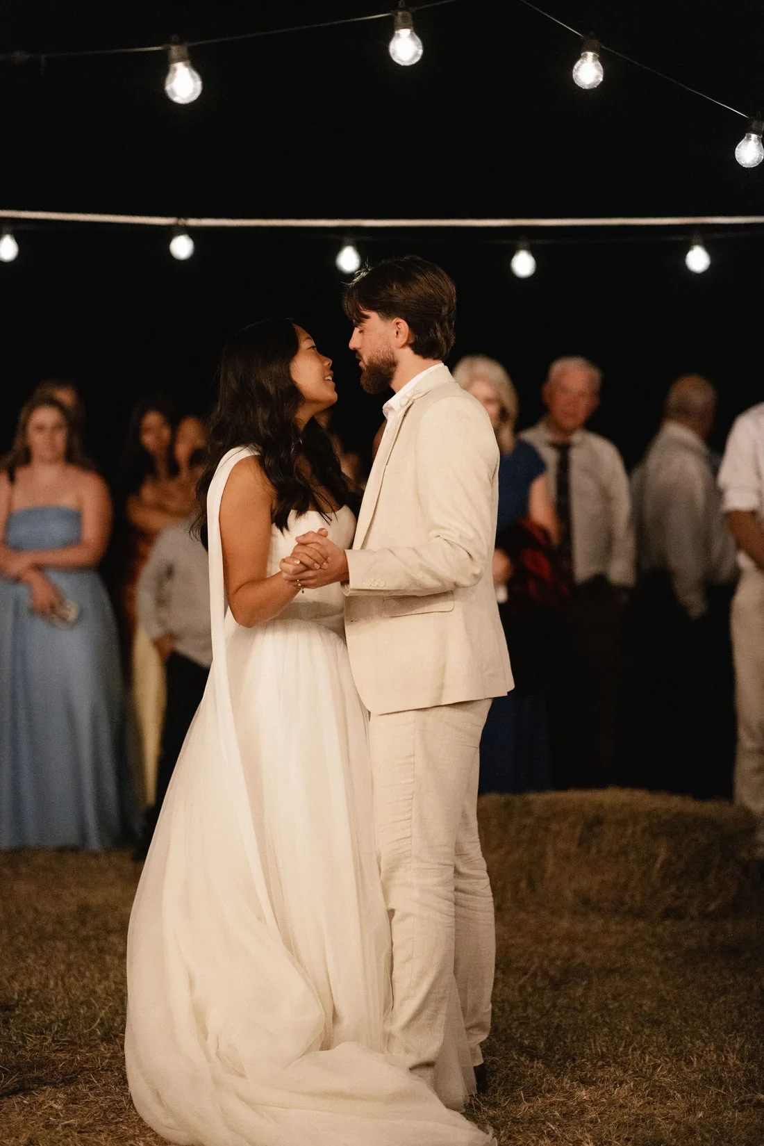 Sarah and Hamish sharing their first dance under string lights at night