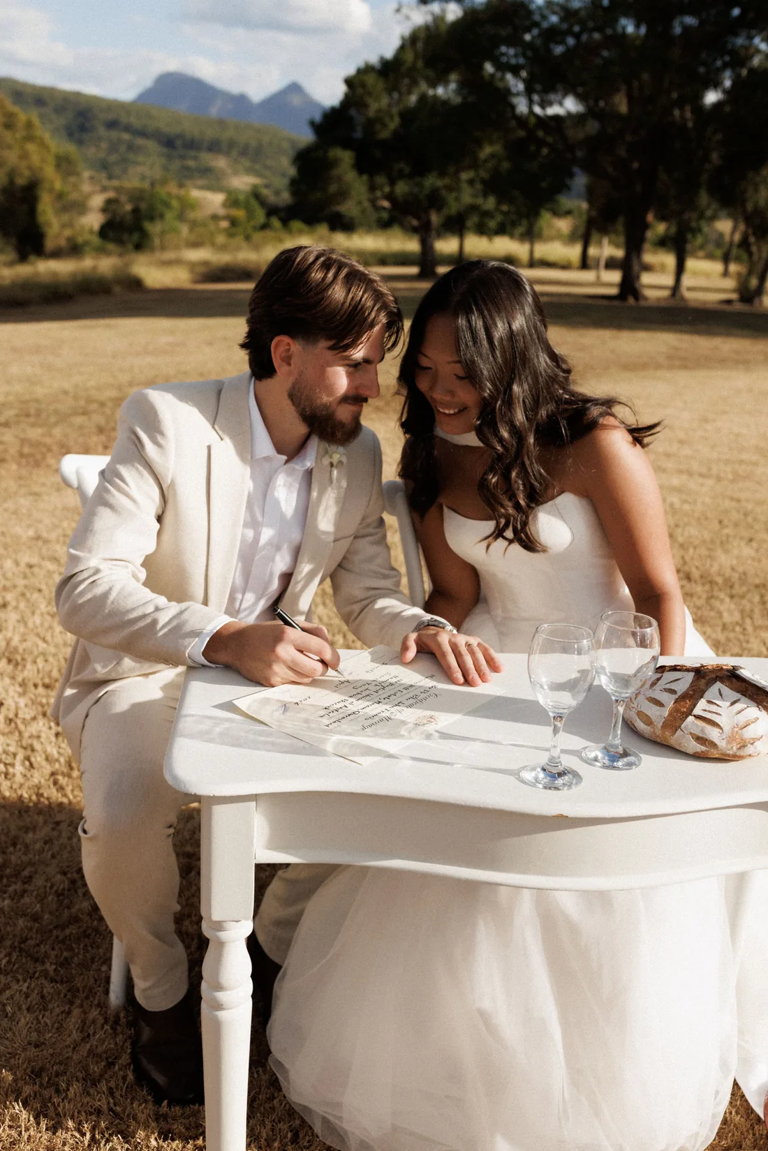 Hamish and Sarah signing the wedding register, mountain views behind