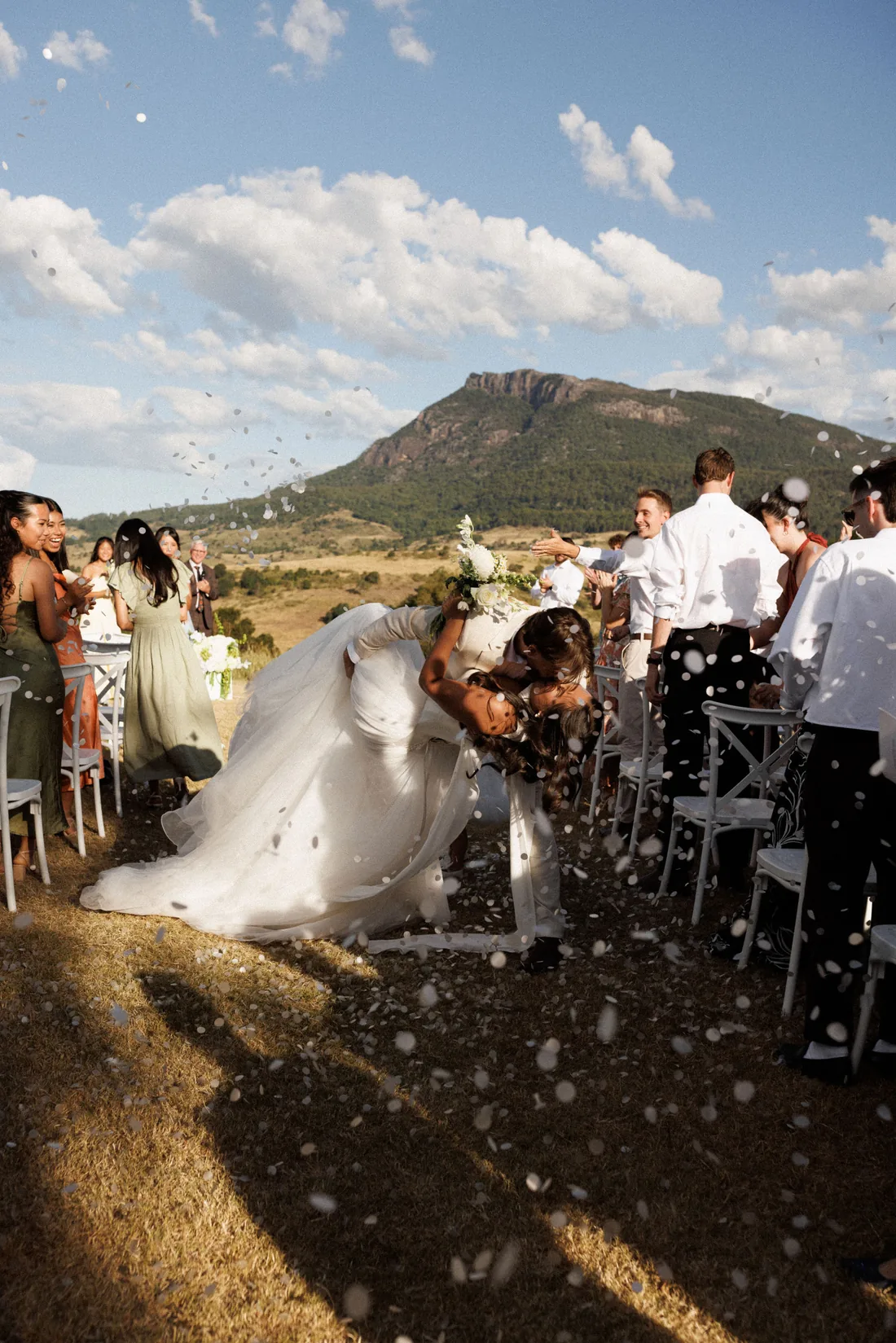 Hamish and Sarah embracing as guests throw confetti after the ceremony