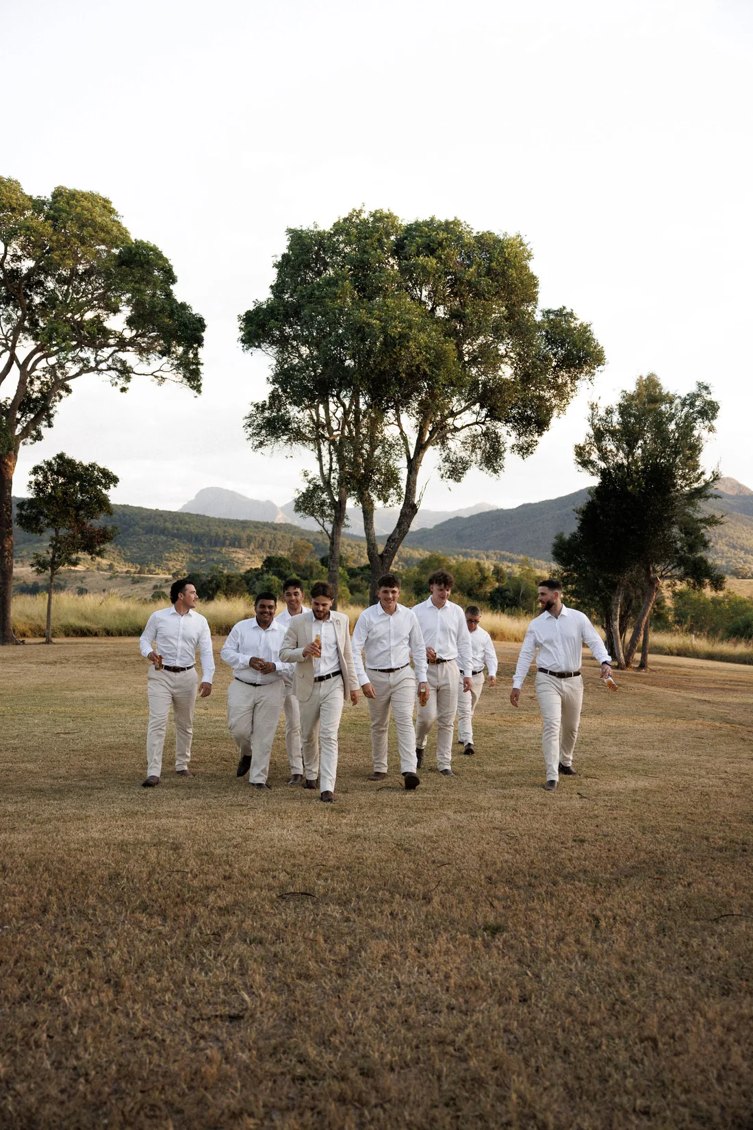 Groomsmen walking together across the lawn at golden hour