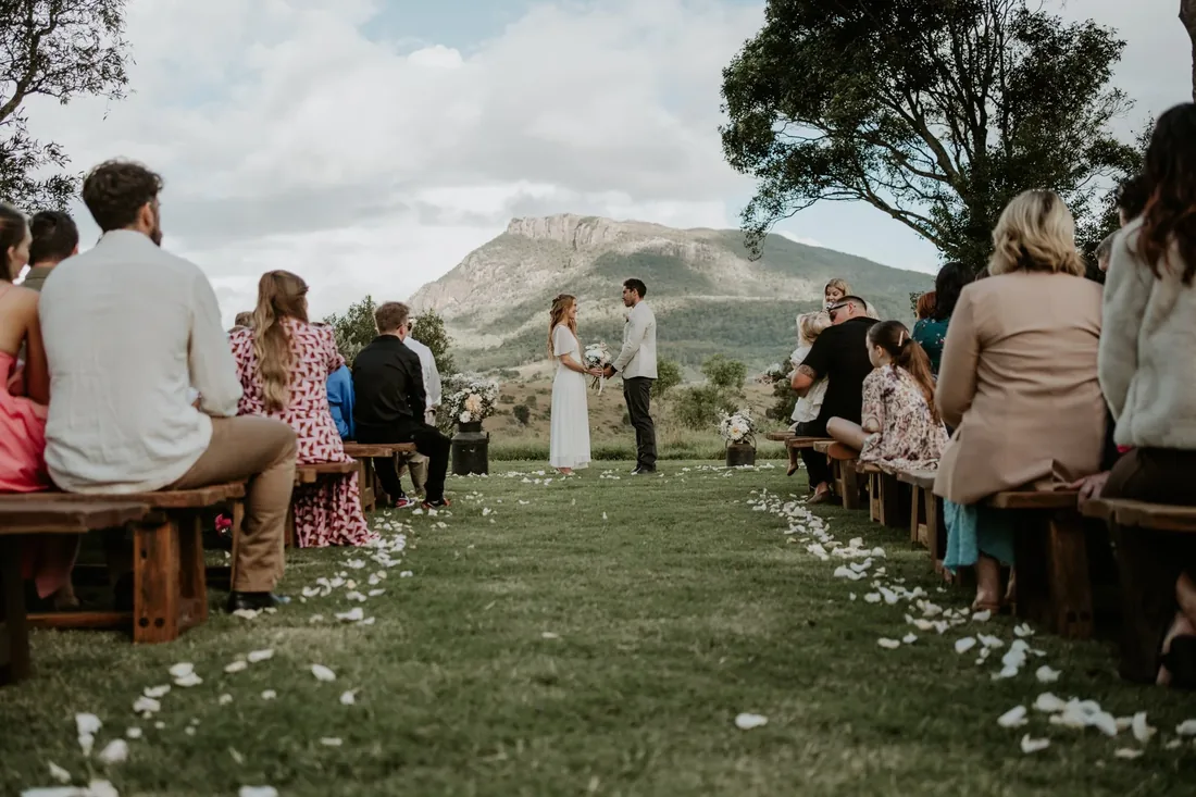 Ceremony in progress at Maroon Hill Estate, guests seated on timber benches facing the mountain