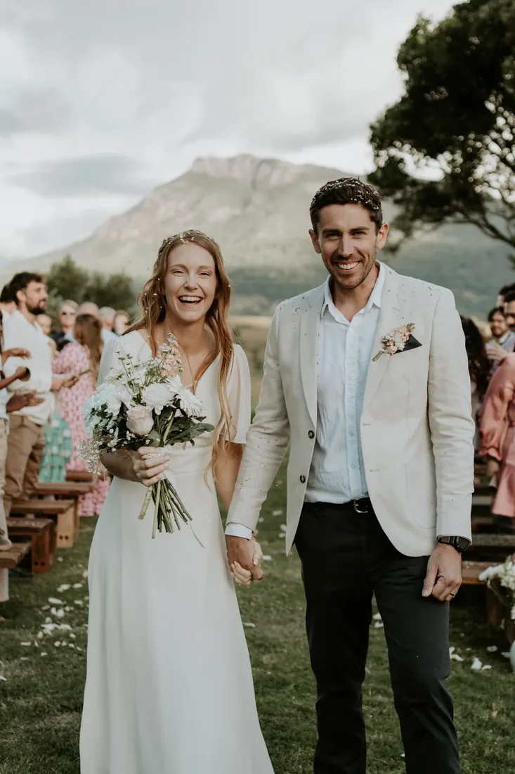 Sarah and Rhys laughing together walking back up the aisle after their ceremony