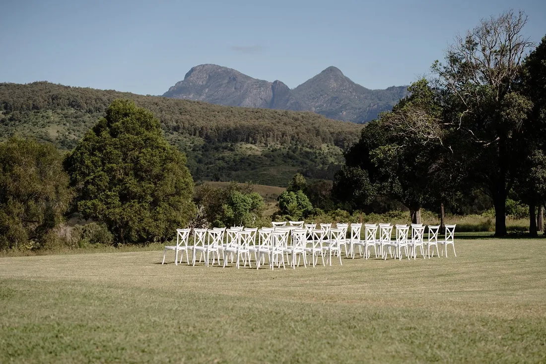 Rows of white cross-back chairs set up for the ceremony with mountain views