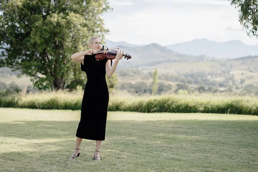 Violinist playing for guests on the lawn, mountains in the background