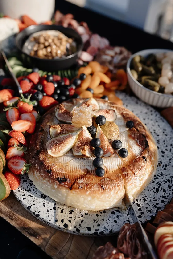 Baked brie topped with figs, honeycomb and blueberries on a grazing table