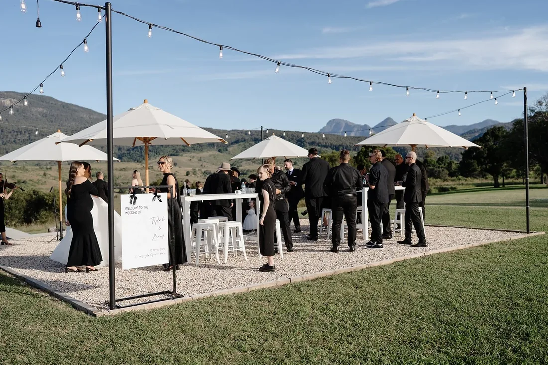 Guests mingling at the cocktail bar under string lights and market umbrellas at golden hour