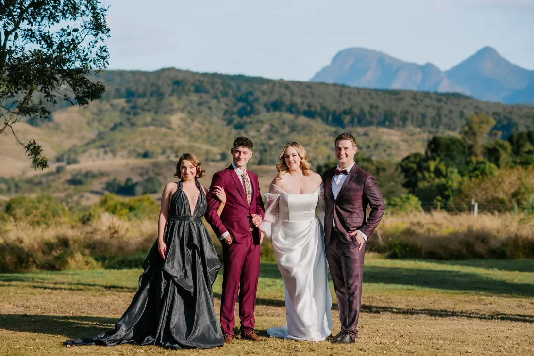 Four models in eveningwear and bridal styles standing together with mountain views behind them