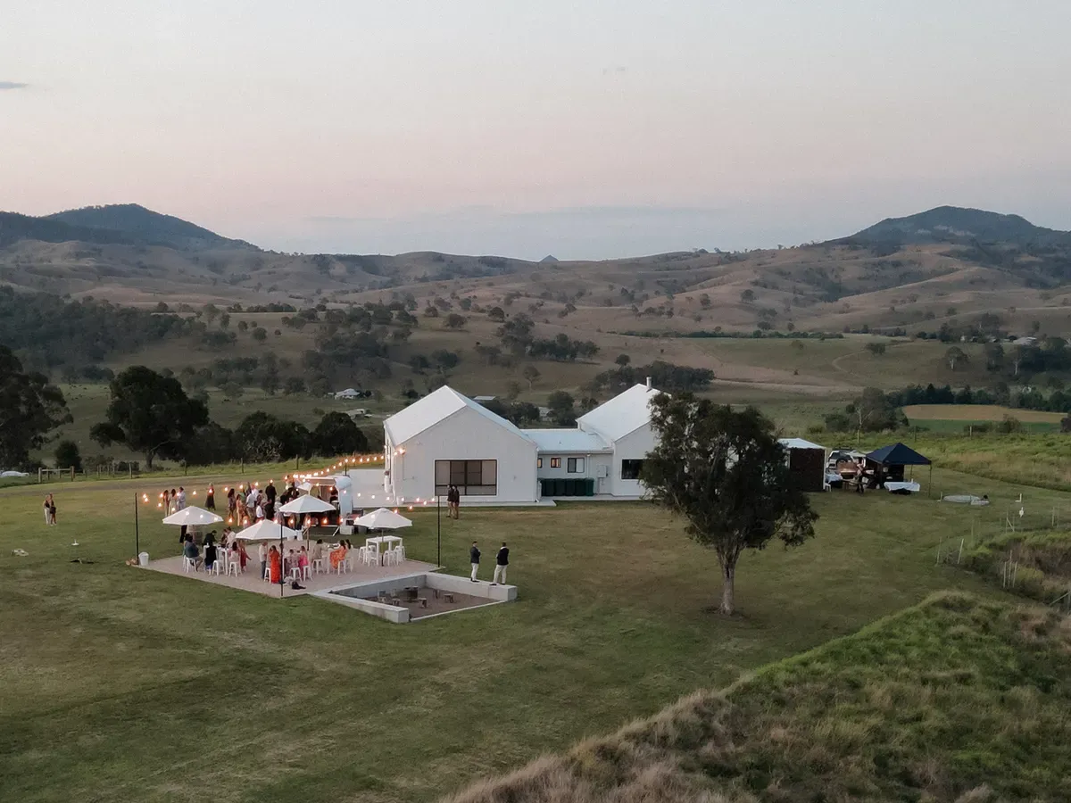 Aerial view of The Cocktail & Firepit Area at dusk, with the homestead and hills beyond