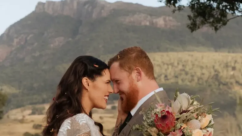 Abby and Liam forehead to forehead with Mount Maroon behind them