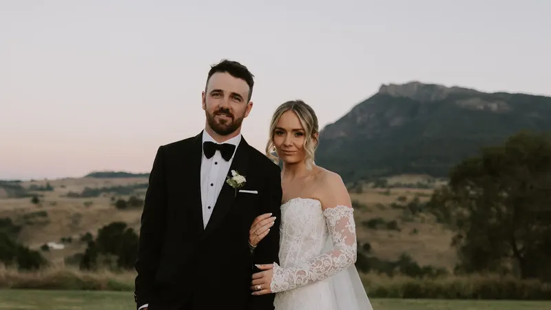 Kate and Jake arm in arm on the lawn at dusk, Mount Maroon behind them